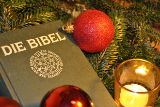 Bibel mit Tannenzweigen und Kerze an Heiligabend